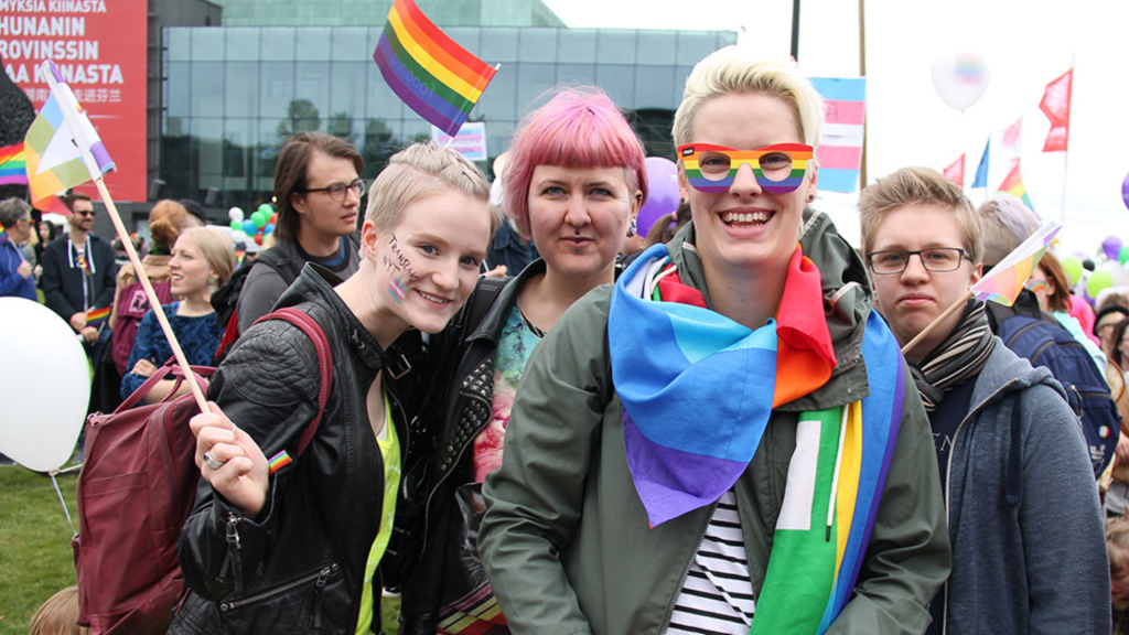 4 young people with rainbow accessories pose at Helsinski Pride