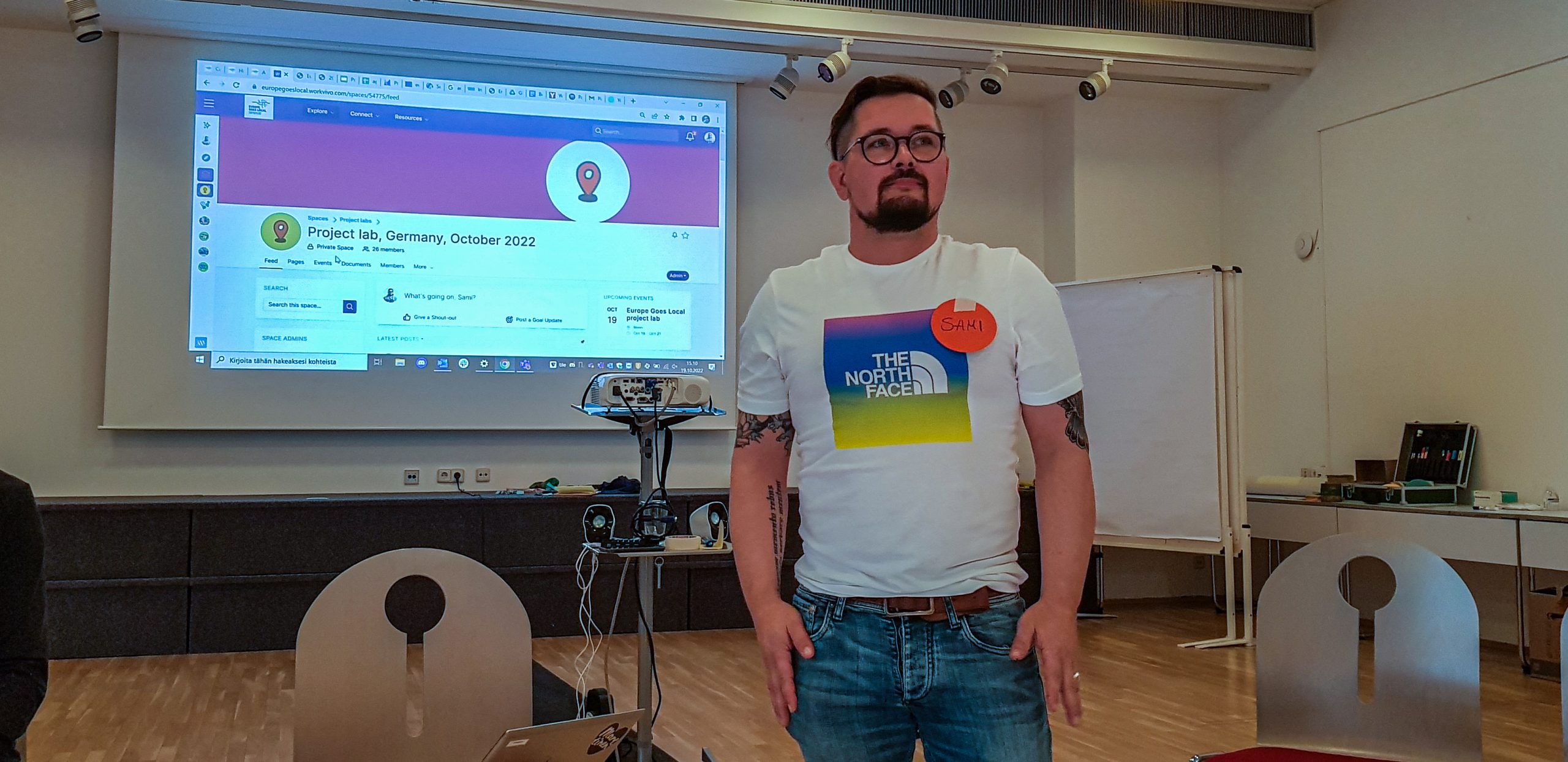 One person standing in front of a screen that says "Project Lab Germany, October 2022"