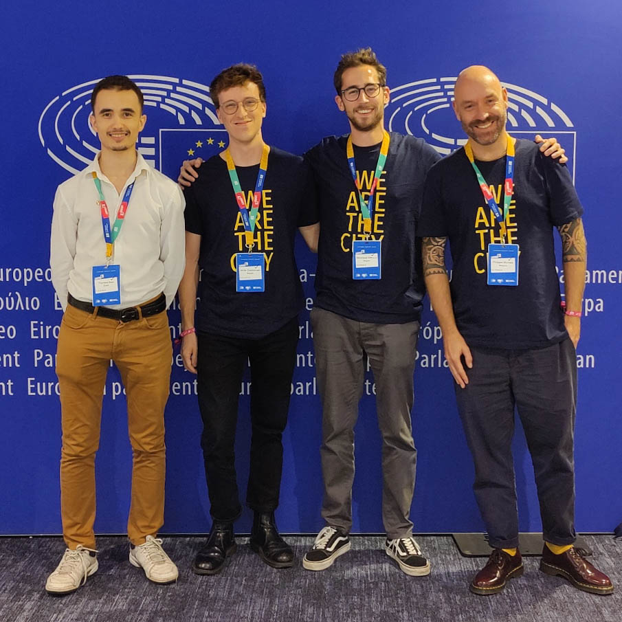 Four people with a t-shirt "We Are The City" pose together