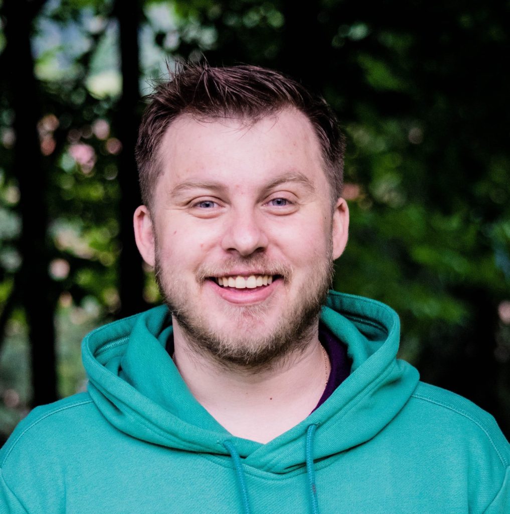 An image of a smiling man in a green sweatshirt